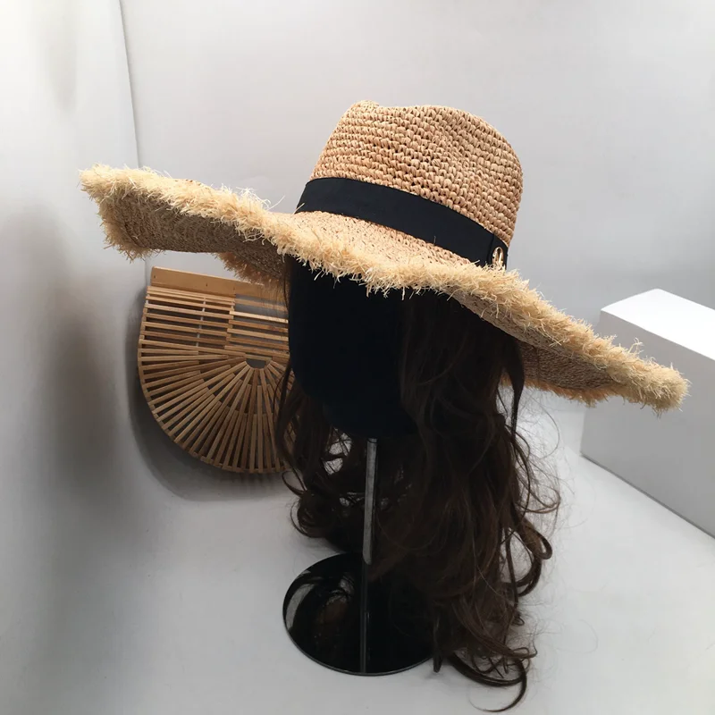 Web-kendte med stor lafite græs udhæng den stilfulde parasol hat den kvindelige sea beach resort er forhindret sole sig i stråhat